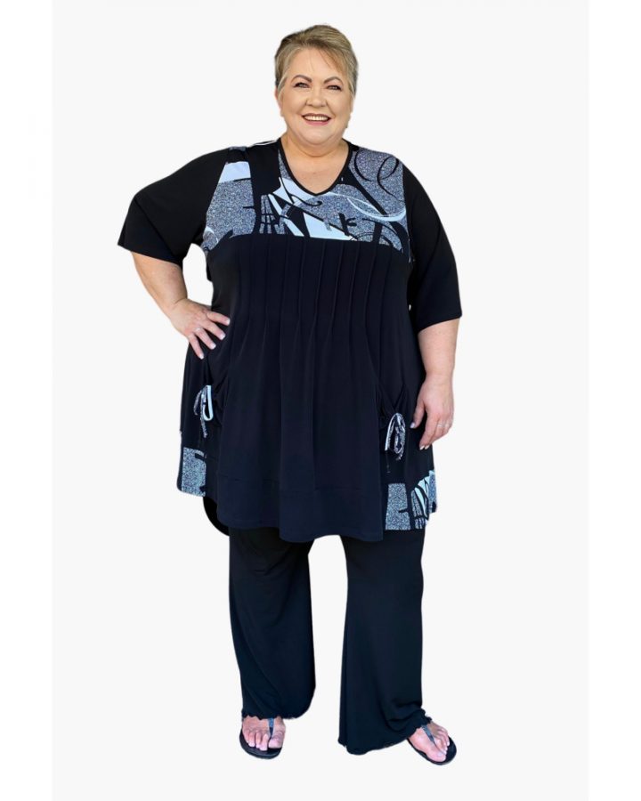 Reana wearing a Plus size, 6XL pintuck top and 6XL black bootlegs.